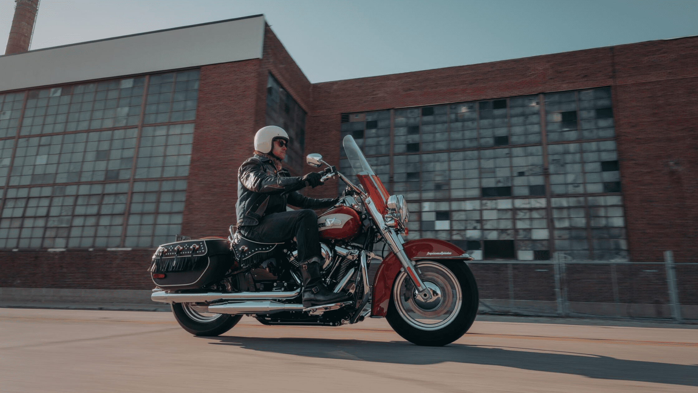 Rider on a 2024 Harley-Davidson Hydra-Glide Revival cruising past industrial buildings near Covington, GA, highlighting the vintage-inspired design and urban riding experience.