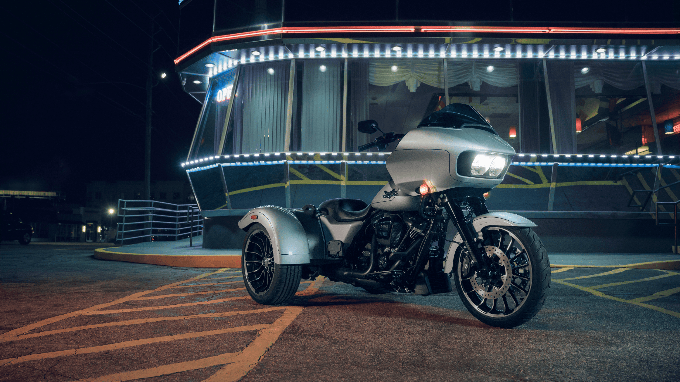 2025 Harley-Davidson® Road Glide® 3 parked outside a diner near Covington, GA, showcasing custom lighting and aggressive three-wheel styling at night.