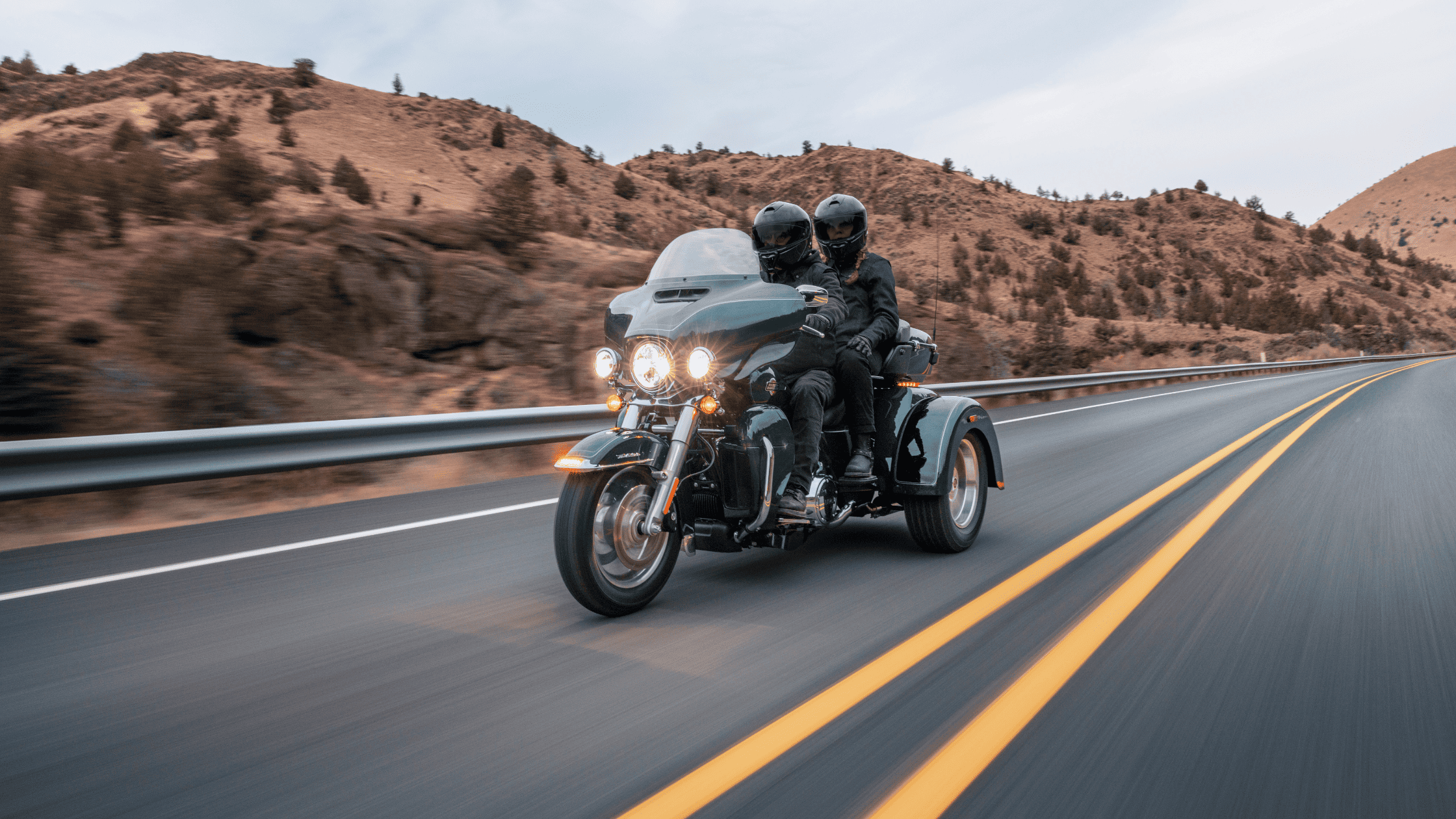 Couple cruising through the scenic hills near Covington, GA, on a 2025 Harley-Davidson® Tri Glide® Ultra three-wheeler with touring storage and LED lighting.